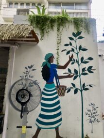 A wall mural of a girl touching the green leaves for poem because my thoughts are hands